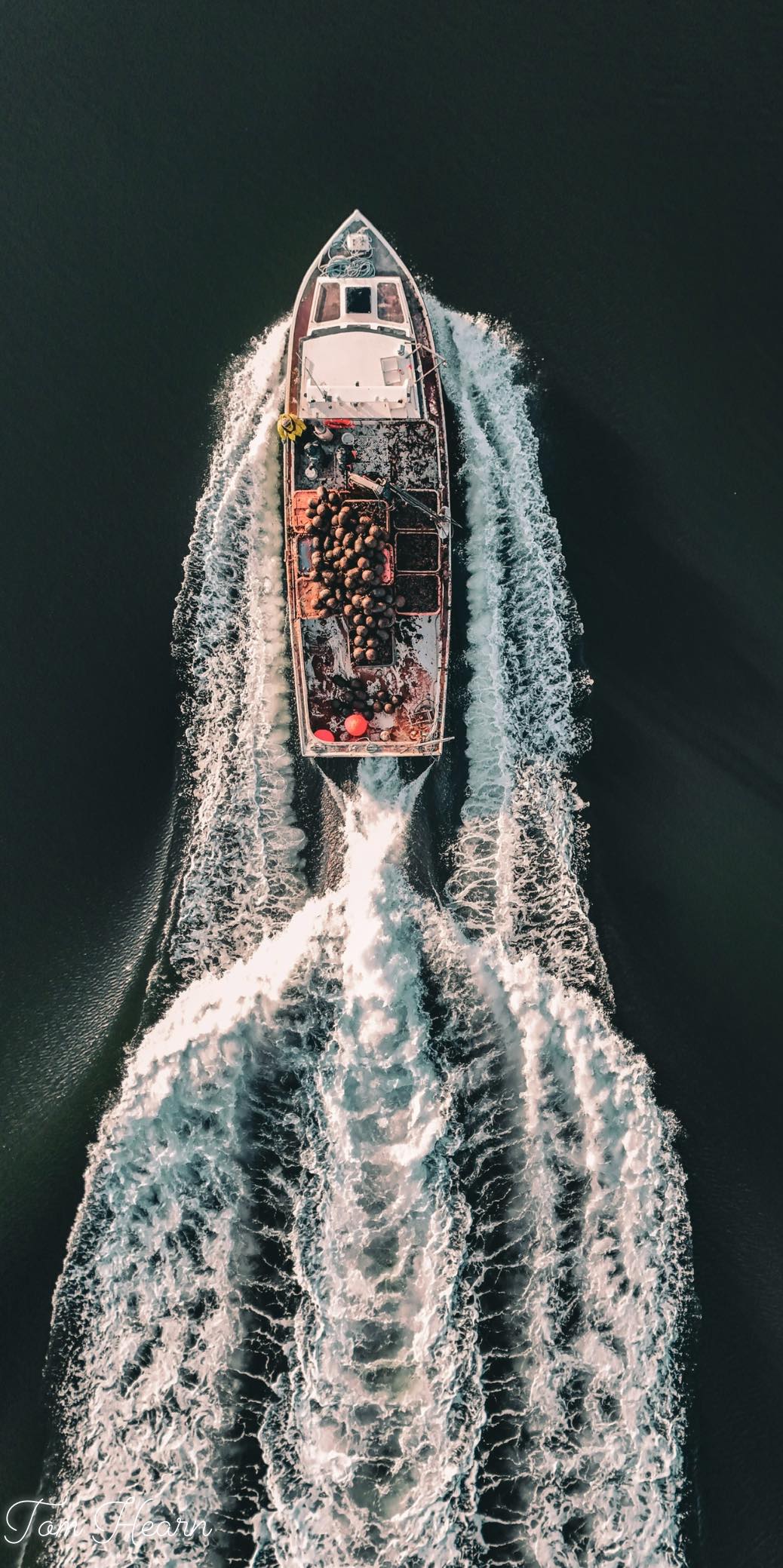 Aerial view of mussel harvesting boat cutting through the water